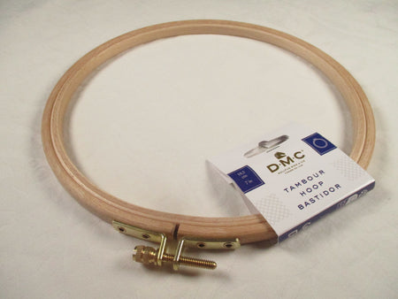 Wooden embroidery hoop with DMC packaging on a light background