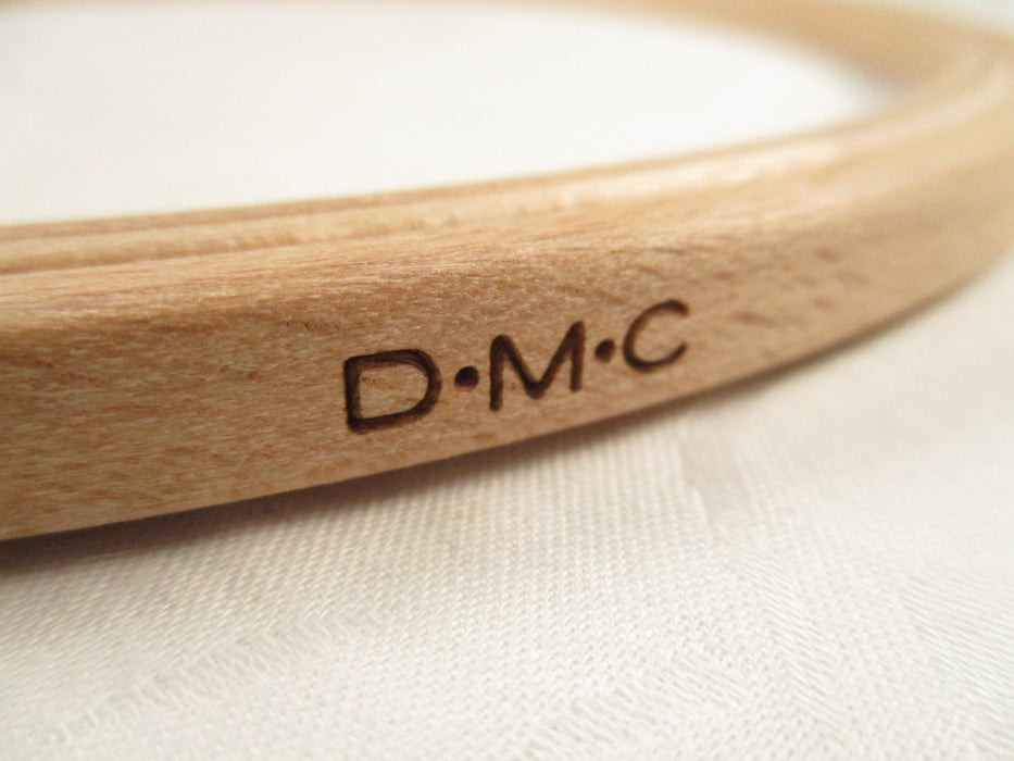 Wooden ring with 'D.M.C.' engraving on a light fabric background