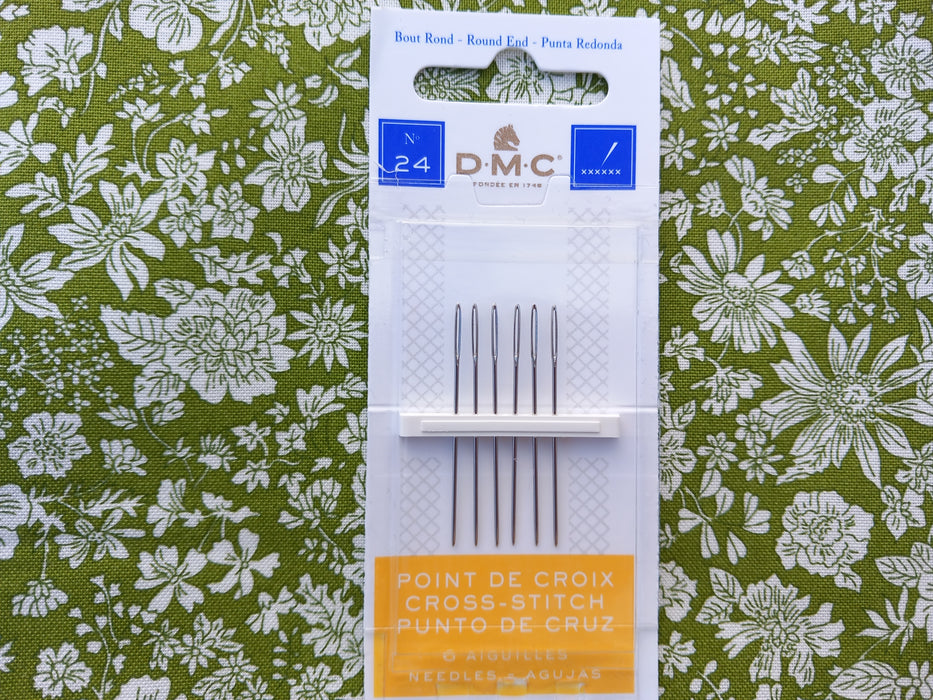 Pack of DMC Size 24 cross-stitch needles on floral background
