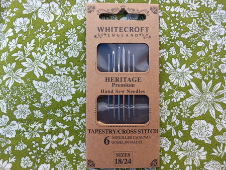 Pack of Whitecroft England Heritage premium hand sew needles on a floral fabric background