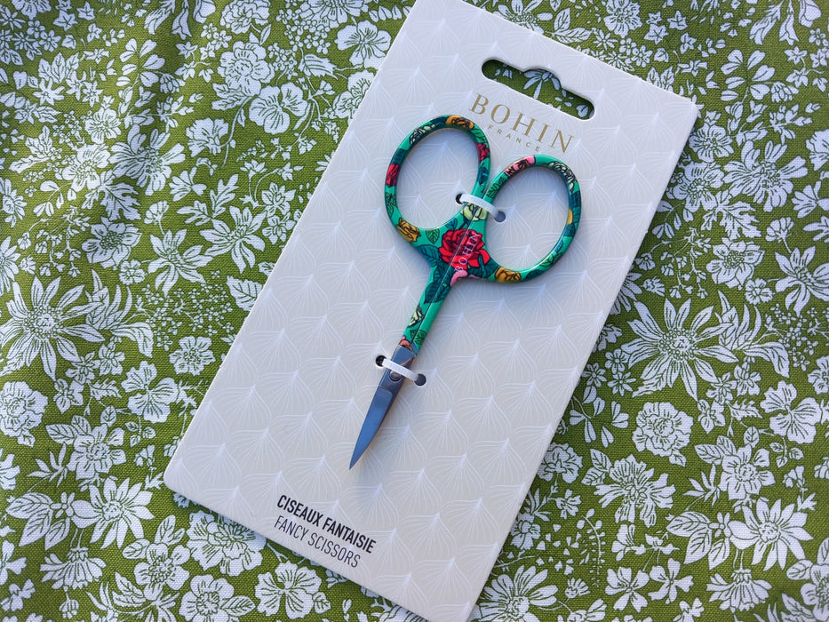 Colorful scissors on a white card with 'Bohin' branding against a floral patterned background
