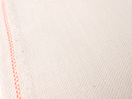 Close-up of white fabric with a red thread seam on a light background