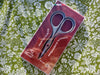 Package of embroidery scissors on a floral fabric background